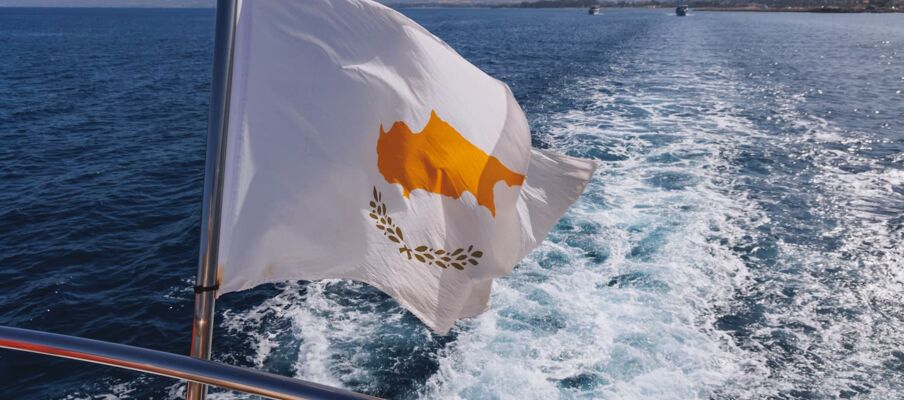 The flag of Cyprus with the sea and coastline in the background.