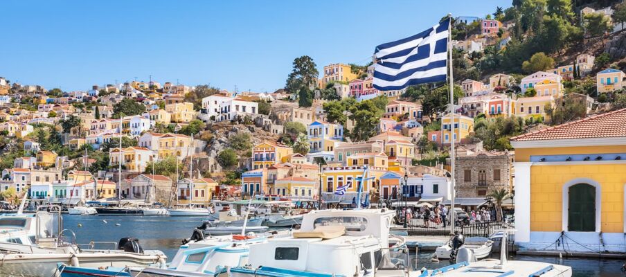 The flag of Greece with a city in the background showing a port.