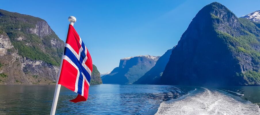The Norwegian flag with a fjord background