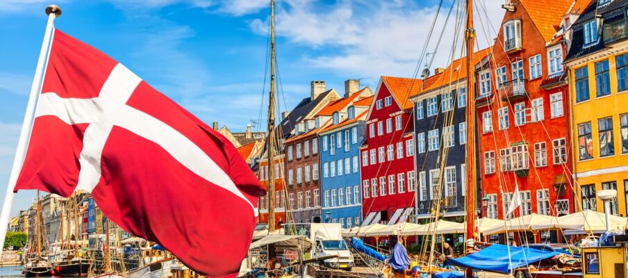 The flag of Denmark with the capital in the background showing a harbour.