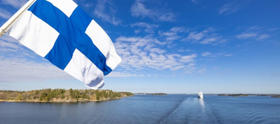 The flag of FInland with the sea and coastline in the background.