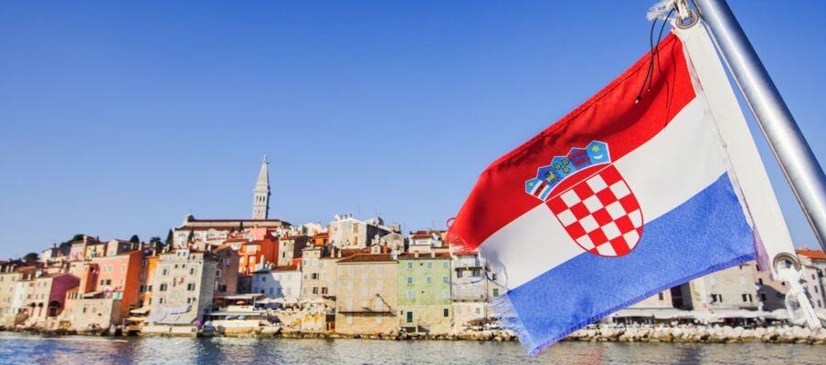 The flag of Croatia with a city in the background, showing the coastline.