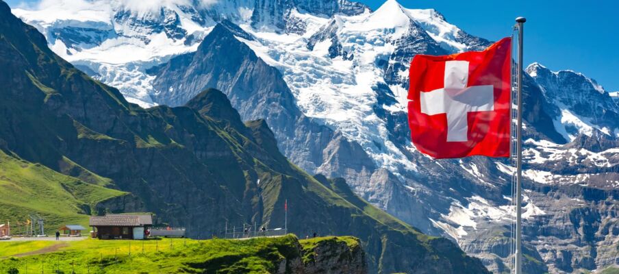 The flag of Switzerland with mountains in the background